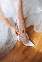 Braut Schuhe. das Mädchen trägt Stilettos. elegant Damen Schuhe. schön Einzelheiten. das Braut setzt auf ihr Schuhe und bereitet vor zum das Hochzeit Zeremonie foto