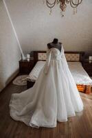 Schlafzimmer Innere mit Hochzeit Kleid bereit zum das Zeremonie. ein schön üppig Hochzeit Kleid auf ein Mannequin im ein Hotel Zimmer. foto