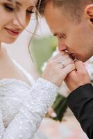 Hochzeit Kuss. Bräutigam Küsse Braut Hand. hochzeit Liebe. Nahansicht von ein jung Mann küssen seine Ehefrauen Hand mit Gold Ring während Herstellung ein Ehe Vorschlag. foto