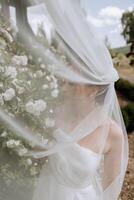 Porträt von ein schön jung Braut im ein Weiß Kleid mit ein lange Schleier und ein Herrlich Frisur. lächelnd Braut. Hochzeit Tag. Herrlich Braut. Hochzeit. foto