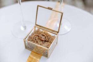 ein Glas Box mit Gold Hochzeit Ringe im das Mitte. Einzelheiten beim das Hochzeit. Hochzeit Zeremonie von Hochzeit. foto