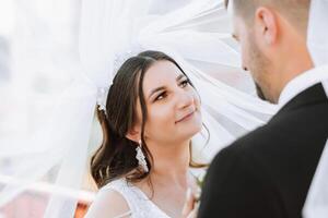 Nahansicht Foto von ein Hochzeit Paar suchen jeder andere im das Augen im Natur. das Braut und Bräutigam aussehen jeder andere im das Mitte von Natur. Zärtlichkeit und Liebe im das Augen.