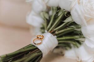 Hochzeit Strauß. Weiß Schnitt Rosen, Grün Samen Köpfe und Blätter. Grün Stängel und Weiß Band und Gold Hochzeit Ringe. foto