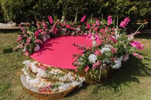 das Rosa Bühne ist dekoriert mit Blumen auf das Hintergrund von das Wald. Vorbereitung zum das Hochzeit Zeremonie foto