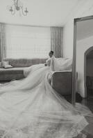 jung Brünette im lange Hochzeit Kleid und Schleier im Hotel Zimmer. ein charmant Braut, voll Länge, im ein großartig Weiß Kleid auf das Morgen Vor das Hochzeit. foto