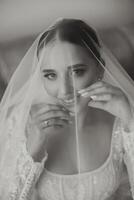 schön jung Braut halten Schleier im Weiß Hochzeit Kleid, Porträt von Brünette Braut im Hotel Zimmer, Morgen Vor Hochzeit. foto