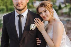 das Braut und Bräutigam umarmen. das Braut sanft Umarmungen das Bräutigam durch das Schultern. schön Hochzeit Paar. das Konzept von Romantik im ein Jungvermählten Beziehung. Flitterwochen. foto