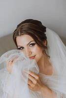 Porträt von das Braut im das Hotel Zimmer. ein schön jung Mädchen ist gekleidet im ein Weiß Hochzeit Kleid. modern Hochzeit Frisur. natürlich bilden. foto