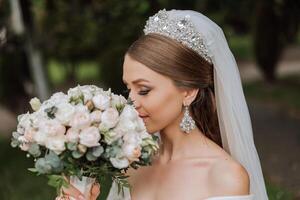 ein schön Braut im ein unglaublich schön Kleid genießt ein Strauß und schnüffelt Es. Sommer- Hochzeit. ein luxuriös Braut. foto