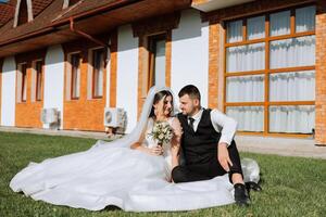 schön Paar Sitzung und umarmen draußen auf ihr Hochzeit Tag, entspannend auf das Beste Sommer- Tag. ein gut aussehend Bräutigam und ein elegant Braut im ein großartig Hochzeit Kleid. foto