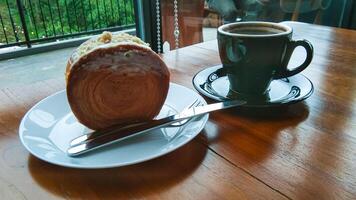 Vanille Cromboloni auf ein Weiß Teller und ein Tasse von Kaffee auf ein hölzern Tisch, sehr köstlich und sieht aus luxuriös foto