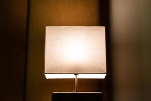 glühend Lampe auf Nachttisch im das Abend. foto
