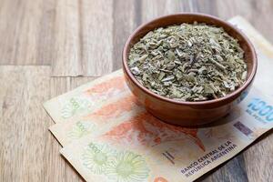 Konzept von das Kosten von Yerba sich paaren. Argentinien Pesos mit Yerba Kamerad im ein Schüssel. foto