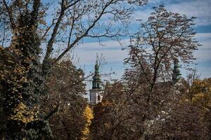 Glocke Turm von das Kirche unter das Herbst Bäume im Krakau foto