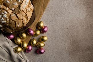 Ostern Kuchen oder Brot kulich mit Mandel mit Schokolade Ostern Eier auf hölzern Schneiden Tafel foto