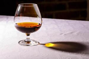 das Blendung von das Glas von Französisch Brandy reflektiert auf Weiß Tab foto