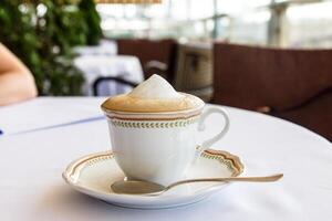 Sascha Cappuccino steht auf ein Untertasse mit Löffel. foto