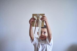 wenig Junge hält ein Kunst Geschenk Zertifikat im seine Hände foto
