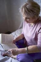 Alten Frau liest ein Buch beim Zuhause foto