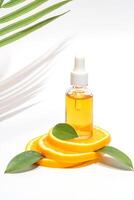 ein hell und erfrischend Anzeige von ein Vitamin c Serum Flasche auf ein Podium gemacht von frisch Orange Scheiben und Grün Blätter. foto