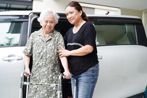 pflegekraft hilft asiatischen älteren frauen mit behinderungspatienten, in ihr auto zu steigen, medizinisches konzept. foto