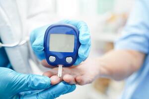 asiatisch Arzt mit Digital Glucose Meter zum prüfen Stichprobe Blut Zucker Niveau zu Behandlung Diabetes. foto