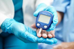 asiatisch Arzt mit Digital Glucose Meter zum prüfen Stichprobe Blut Zucker Niveau zu Behandlung Diabetes. foto