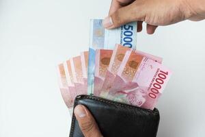 ziehen aus indonesisch Rupiah Geld im ein Leder Brieftasche auf ein Weiß Hintergrund foto