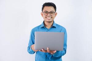lächelnd oder glücklich asiatisch Geschäftsmann mit Brille halten Laptop tragen Blau Hemd isoliert auf Weiß Hintergrund foto