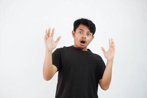 erstaunt oder schockiert jung asiatisch Mann öffnen Hand mit öffnen Mund tragen schwarz t Hemd isoliert auf Weiß Hintergrund foto
