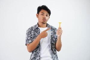 verwirrt jung asiatisch Mann zeigen beim das Rasierapparat mit seine Finger tragen schwarz Hemd isoliert auf Weiß Hintergrund foto