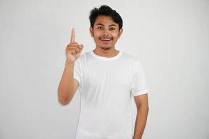 aufgeregt jung asiatisch Mann zeigen Finger oben haben ein gut Idee mit Kopieren Raum tragen Weiß t Hemd isoliert auf Weiß Hintergrund foto