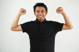 jung asiatisch Mann gegen ein beschwingt Weiß Studio Hintergrund, zeigen Stärke Geste mit Waffen, Symbol von Leistung tragen schwarz Polo t Shirt. foto