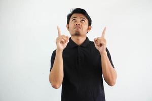 jung asiatisch Mann verwirrt und zeigen beide Hände oben tragen schwarz Polo t Hemd isoliert auf Weiß Hintergrund foto