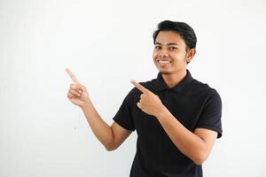 jung asiatisch Mann lächelnd zuversichtlich mit beide Hand zeigen zu das richtig Seite tragen schwarz Polo t Hemd isoliert Weiß Hintergrund foto