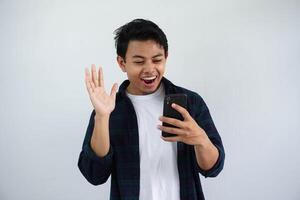 jung asiatisch Mann suchen zu seine Handy, Mobiltelefon Telefon mit Beeindruckend Ausdruck isoliert auf Weiß Hintergrund. foto