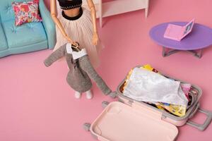 das Puppe setzt Dinge im ein Gepäck. vorbereiten zum reisen. Reise Konzept foto