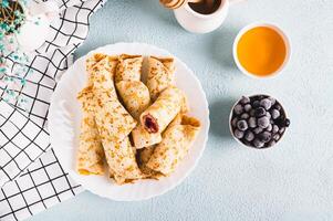 hausgemacht Pfannkuchen Rollen mit Beere Füllung auf ein Teller auf das Tabelle oben Aussicht foto