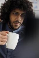 Start oben Unternehmen Geschäft Mitarbeiter Trinken Kaffee und tun Produkt Verwaltung auf Laptop. jung arabisch Unternehmer halten Tee Tasse und vorbereiten Marketing Kampagne auf Computer foto