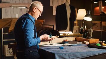 Couturier suchen zum Artikel zu erstellen Mode Sammlung im Schneiderei Werkstatt, erfahren Schneider Arbeiten auf Kleidung Linie mit basteln Fähigkeiten. klein Geschäft Konzept Textil- Industrie. foto