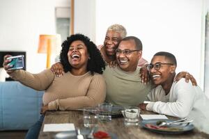 glücklich schwarz Familie haben Spaß nehmen Selfie mit Handy, Mobiltelefon Smartphone Nocken während haben Mittagessen beim Zuhause foto