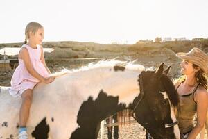 glücklich Farmer Familie Mutter und Tochter haben Spaß Reiten Pferd Innerhalb Ranch foto