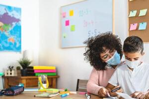 Lehrer Frau mit Kind tragen Gesicht schützend Maske im Vorschule Klassenzimmer während Corona Virus Pandemie - - Gesundheitswesen und Bildung Konzept foto