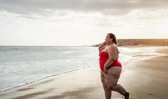 glücklich Plus Größe Frau haben Spaß Gehen auf tropisch Strand während Sommer- Zeit - - kurvig zuversichtlich Menschen Lebensstil Konzept foto