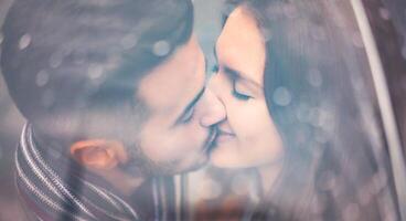 jung Paar küssen unter Regenschirm im regnerisch Tag - - romantisch Liebhaber haben ein zärtlich Moment draussen - - Menschen, Liebe und Beziehung Konzept foto