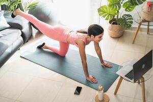 jung Latein Frau tun Pilates virtuell Fitness Klasse mit Laptop beim Zuhause - - Sport Wellness Menschen Lebensstil Konzept foto