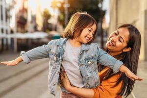 glücklich Filipina Mutter mit ihr Tochter haben Spaß im das Stadt Center - - schön Familie draussen foto