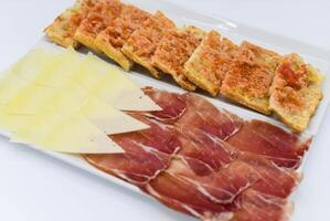 ein Portion von iberisch geheilt Schinken mit Käse und Brot foto