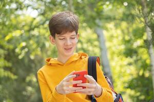 ein jung Junge ist haben ein Video Anruf draußen, halten ein Smartphone im seine Hände. foto