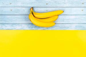 Gelb Bananen Lüge auf ein Blau hölzern Hintergrund und ein Gelb Hintergrund foto